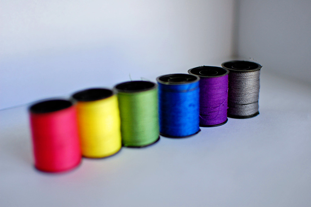 Colourful embroidery thread spools and cotton floss arranged in a rainbow — DMC and Anchor stranded cotton for hand embroidery projects