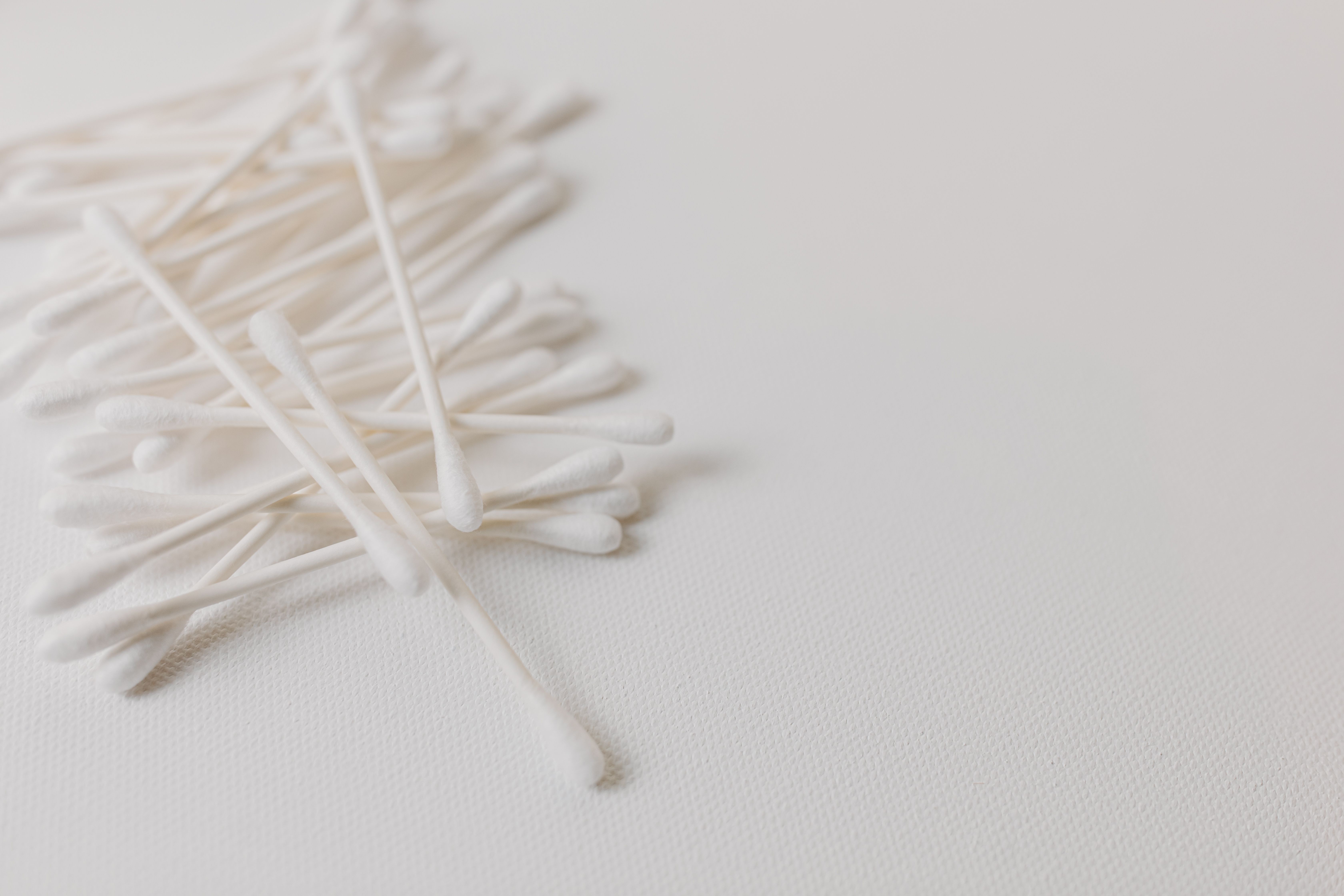 Cotton bud colourfastness test on embroidered fabric — white cotton swab pressed against red and blue thread to check for dye bleeding before washing